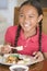 Young girl in dining room eating Chinese food