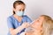 Young girl doctor in a medical mask makes inhalation to an older woman on a white background. Fight nasal congestion and