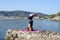 Young girl doing yoga on a small beach pier with a Mediterranean coastal town in the background. Staying fit. Salamba Sirsasana