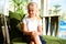 A young girl in a dress sits on an easy chair in a sunny hotel