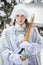 A young girl dressed as a Snow Maiden holds a shovel on her shoulder. Funny shot. Snowy winter. Snow removal. Utilities work