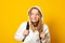 Young girl dressed white hoodie on yellow  background with backpack. Portrait of cool schoolgirl with backpack