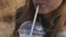 A young girl drinks a milkshake from a plastic glass through a straw.