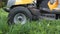 Young girl driving lawn mover cutting green grass in garden. Gardener service concept.