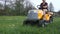 Young girl driving lawn mover cutting green grass in garden. Gardener service concept.