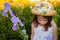 Young Girl in Easter Dress and Hat Stands Among Flowers Looking