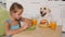 Young girl eating a hamburger - sharing the table with her dog