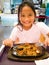 A young girl is eating Sizzling noodle in cast iron serving platters with egg, meats, seafood, vegetables, tofu, and noodles