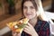 Young girl eating a slice of pizza indoors, girl student gives pizza, close-up