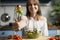 Young girl eating vegetarian salad at home in the kitchen, she is trying healthy food at the wooden table