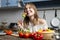 Young girl eating vegetarian salad at home in the kitchen, she is trying healthy food at the wooden table