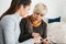 A young girl explains to an elderly woman how to use a tablet or shows some application or teaches you how to use a