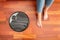 Young girl feet at home with a round smart automatic vacuum cleaner passes to clean the floor, controlling machine housework robot