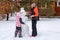 Young girl and female adult making snowman together on cottage backyard in daytime having walk with trees covered with