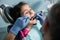 Young girl on the first dental visit. Senior pediatric dentist treating patient girl teeth at the dental office