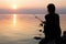 Young girl fishing at sunset near the sea