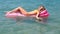 Young girl floating on a mattress in the sea