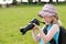 Young girl in a floppy hat using a large digital camera