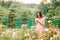 Young girl in a flower garden among beautiful roses. Smell of roses