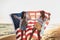 Young girl friends enjoys a sunny day on the beach. They`re holding an american flag