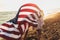 Young girl friends enjoys a sunny day on the beach. They`re holding an american flag