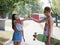 A young girl giving five her cute boyfriend with a longboard on a blurred park background. Relationship and love concept