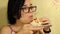 A young girl with glasses at home is eating Shawarma over a plate.