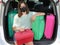 Young girl with glasses and mask with suitcases and car trunk loaded for vacation