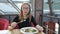 A young girl with glasses sitting in a cafe eating a Caesar salad