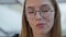 A young girl with glasses sitting in a cafe eating a Caesar salad