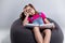 Young girl in glasses sleeping with a book on a gray bean bag