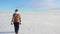 A young girl goes merrily and jumps on a snow-covered field. Winter sunny fun scene with a road and a snowy field