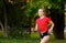 A young girl goes in for sports outdoors. woman in shorts and red t-shirt runs in nature
