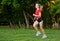 A young girl goes in for sports outdoors. woman in shorts and red t-shirt runs in nature