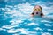 Young girl in goggles and cap swimming breast stroke style