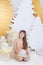 Young girl in golden dress laughs and enjoys gift. Little girl opening magical christmas present at home. child holds christmas pr