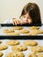 Young girl grabbing cookies from a baking tray