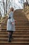 Young girl in gray coat climbs stairs in park in autumn