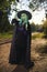 Young girl with green hair and skin suit of witch in forest. Halloween time