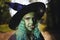 Young girl with green hair and skin suit of witch in forest. Halloween time