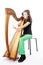 Young girl in green pants plays harp in studio