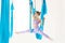 Young girl gymnast in sportswear doing stretching on blue hammock in white studio. Concept aero fly yoga