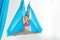 Young girl gymnast in sportswear doing stretching on blue hammock in white studio. Concept aero fly yoga