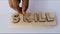 Young girl hand places macro of the word skill of the wooden letter blocks. Concept of future.