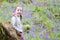 Young girl happy smiling picking bluebell flowers outside in spring summer forest woodland