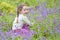 Young girl happy smiling picking bluebell flowers outside in spring summer forest woodland