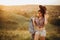 Young girl in hat and denim shorts walks around the field at sunset