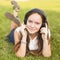 Young girl in headphones enjoys the music lying on the green grass. Pleasure.