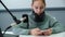 Young girl with headphones on shoulders sitting in sound studio on radio opposite microphone. Radio presenter with