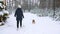 Young girl with his beagle dog are walks through a snowy winter forest. Outdoor walking. Mans best friend. Slow motion